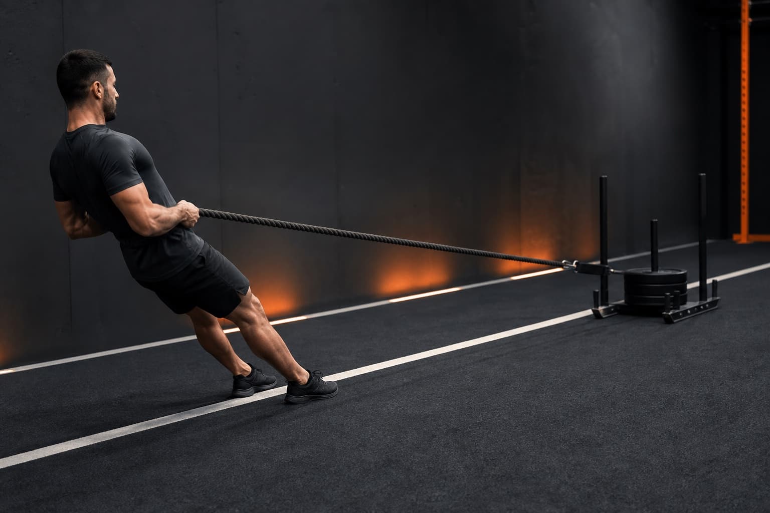 Athlete leaning back with a braced torso while pulling a weighted sled by rope