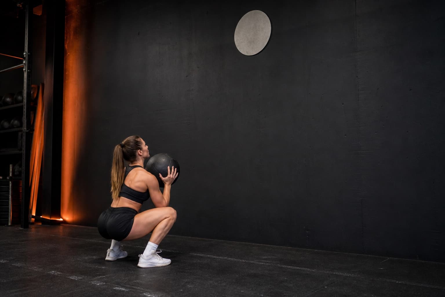 Athlete receiving a wall ball at the chest in a balanced full squat below the target