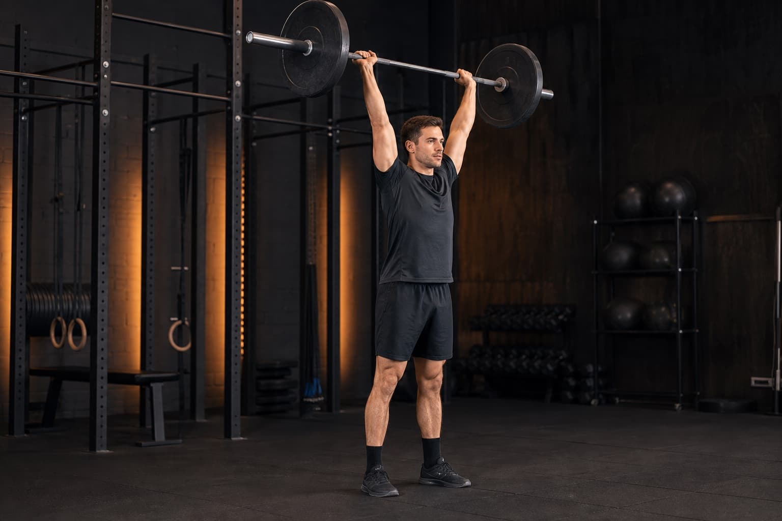 Athlete finishing a barbell thruster with the bar stacked over the middle of the feet